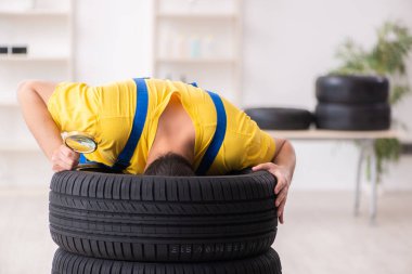 Atölyede lastiği olan genç bir erkek tamirci.