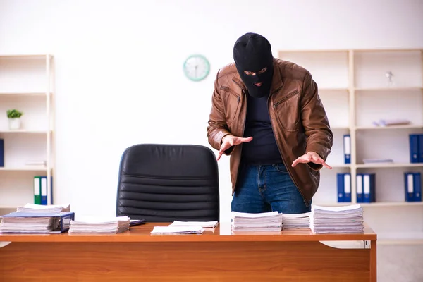 Junger Mann mit Sturmhaube stiehlt Informationen aus Büro — Stockfoto