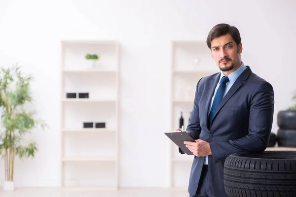 Joven inspeccionando neumáticos en la oficina — Foto de Stock