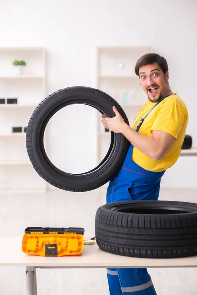 Mladý pracovník garáže s pneumatikou v dílně — Stock fotografie