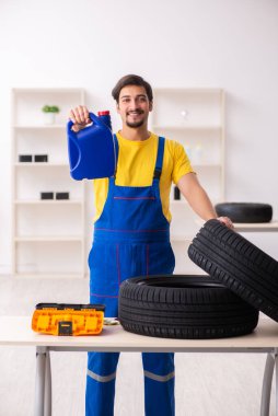 Atölyede lastiği olan genç bir erkek tamirci.