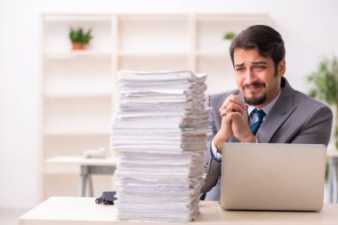 Ofisteki aşırı işten memnun olmayan genç bir erkek işçi.