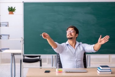 Tahtanın önündeki genç erkek öğretmen.