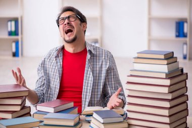 Genç bir erkek öğrenci ve sınıfta çok fazla kitap var.
