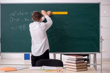 Okul çocuğu tahtanın önünde geometri okuyor.