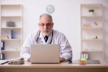 Klinikte çalışan yaşlı erkek doktor.