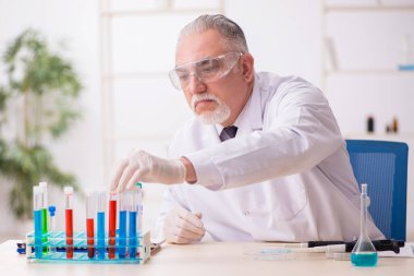 Laboratuvarda çalışan yaşlı bir kimyager.