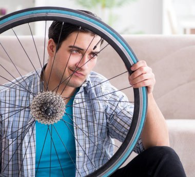 Evde bisiklet tamir eden genç bir adam.