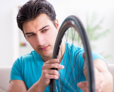 Evde bisiklet tamir eden genç bir adam.