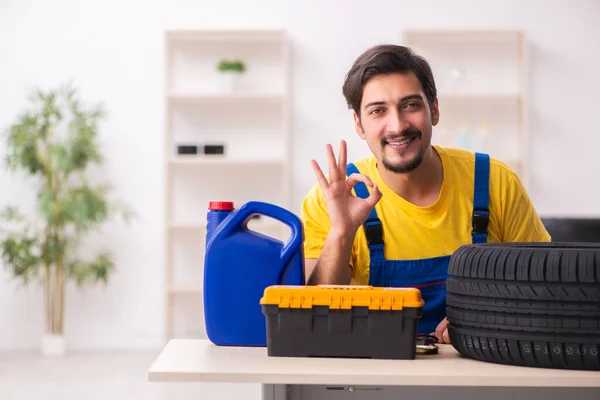 Jovem garagista do sexo masculino com pneu na oficina — Fotografia de Stock