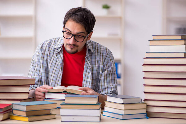 Young male student and too many books in the classroom