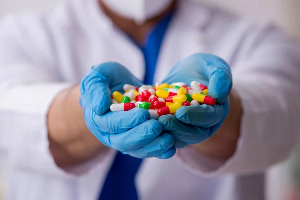 Joven médico masculino y demasiadas pastillas — Foto de Stock