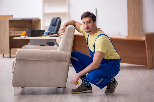 Joven carpintero masculino reparando sillón en la oficina —  Fotos de Stock