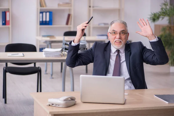 Starý muž zaměstnanec sedí na pracovišti — Stock fotografie