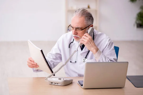 Klinikte çalışan yaşlı erkek doktor. — Stok fotoğraf