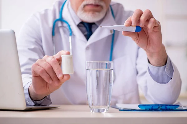 Old male doctor working in the clinic — Stock Photo, Image