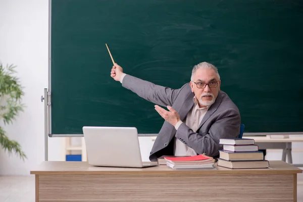 Oude mannelijke leraar voor schoolbord — Stockfoto