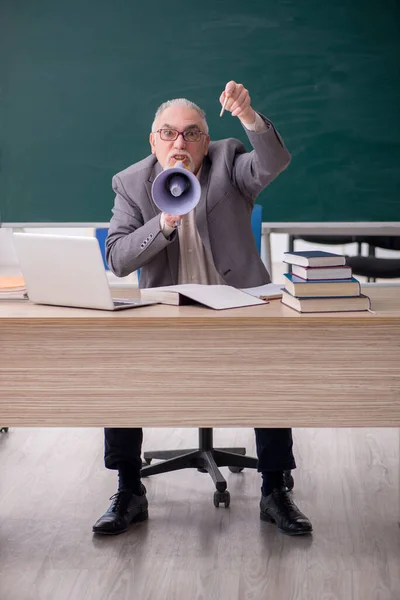 Starý učitel drží megafon před tabulí — Stock fotografie