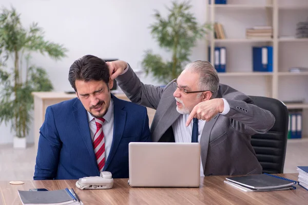Dos empleados masculinos que trabajan en la oficina en concepto de intimidación —  Fotos de Stock