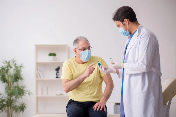 Yaşlı erkek hasta aşılama bölümünde genç bir erkek doktor. — Stok fotoğraf