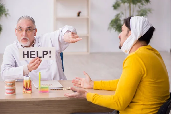 Jeune homme visitant un dentiste masculin expérimenté — Photo