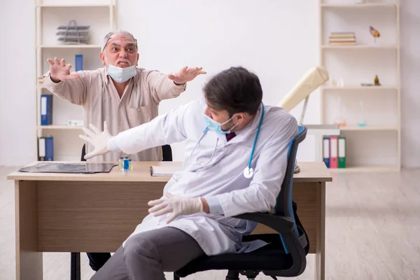 Yaşlı erkek hasta, salgın sırasında genç erkek doktoru ziyaret ediyor. — Stok fotoğraf