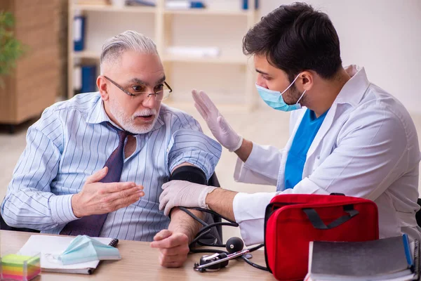 Genç erkek doktor, yaşlı işadamını iş yerinde ziyaret ediyor. — Stok fotoğraf