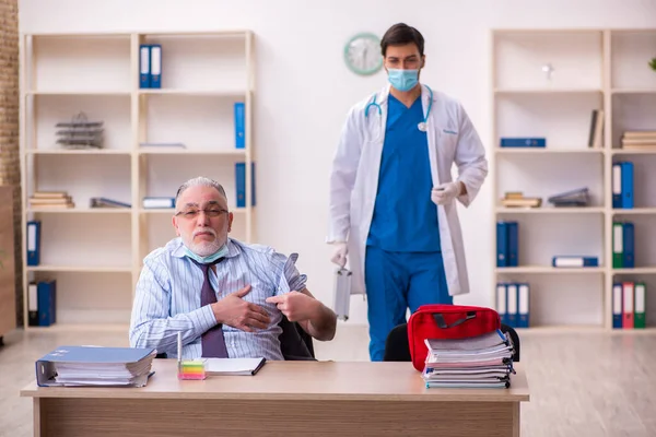 Młody lekarz odwiedził starego biznesmena w miejscu pracy — Zdjęcie stockowe