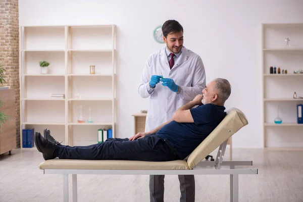 Old male patient visiting young male doctor in vaccination conce — Stock Photo, Image