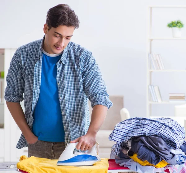 Jovem marido fazendo roupas de engomar em casa — Fotografia de Stock