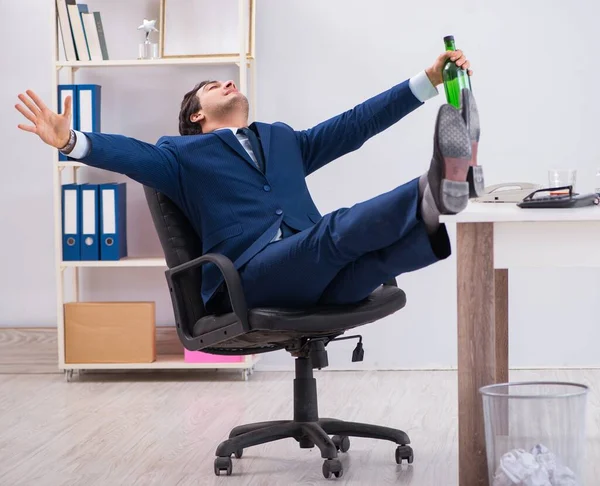 Empleado joven de negocios bebiendo en la oficina en el escritorio — Foto de Stock