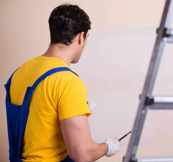 Empregado jovem empreiteiro aplicando gesso na parede — Fotografia de Stock