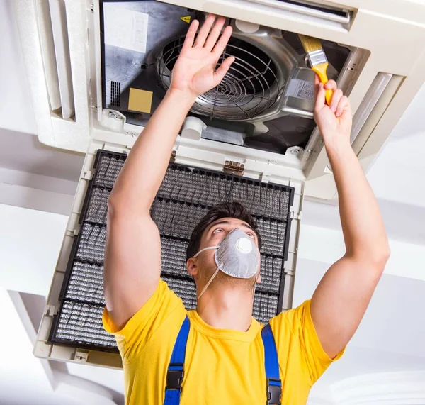 Repairman repairing ceiling air conditioning unit