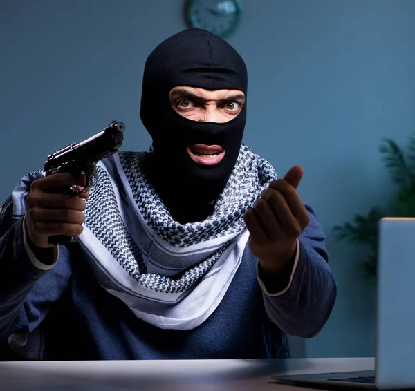 Terrorist inbrottstjuv med pistol arbetar vid datorn — Stockfoto