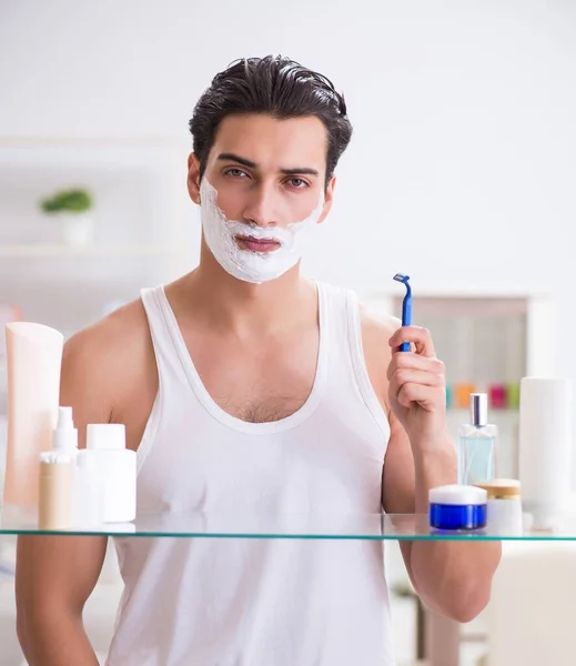 Νέος όμορφος άντρας ξυρίζεται νωρίς το πρωί στο σπίτι. — Φωτογραφία Αρχείου