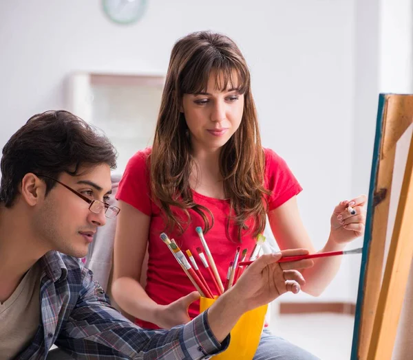 Artist coaching student in painting class in studio