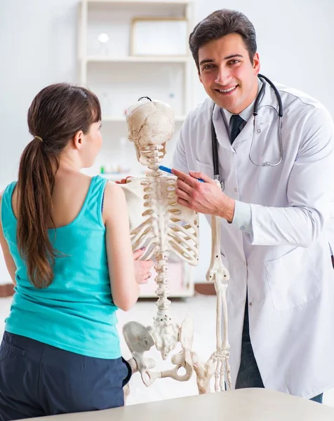 Doctor showing type of injury on skeleton to patient — Stock Photo, Image