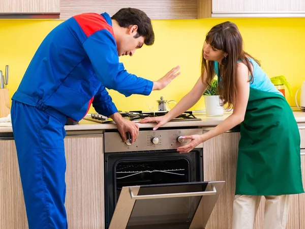 Mulher com empreiteiro na cozinha discutindo reparação — Fotografia de Stock