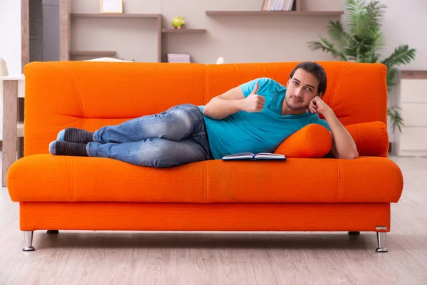 Junge männliche Studentin sitzt auf dem orangefarbenen Sofa — Stockfoto