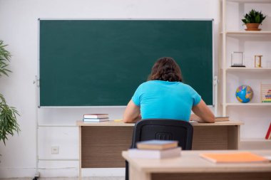 Yeşil panonun önünde genç bir erkek öğrenci.