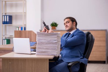 Ofisteki aşırı işten memnun olmayan genç bir erkek işçi.