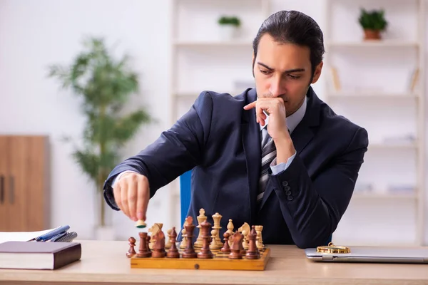 Joven empleado masculino jugando ajedrez en el lugar de trabajo — Foto de Stock