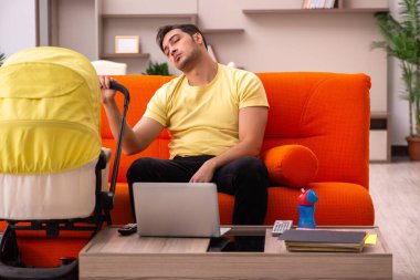 Genç adam evde yeni doğan çocuğa bakıyor.