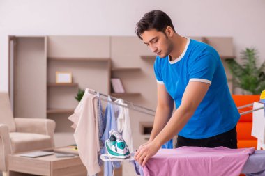 Genç adam evde ütü yapıyor.