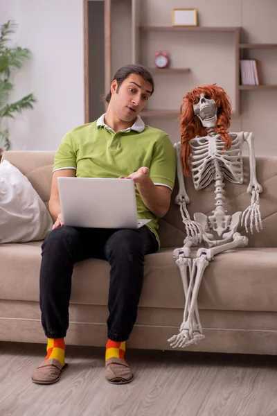 Jongeman zittend op de bank met vrouwelijk skelet — Stockfoto