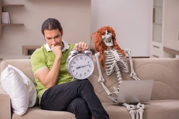 Jovem com esqueleto feminino no conceito de gerenciamento de tempo — Fotografia de Stock