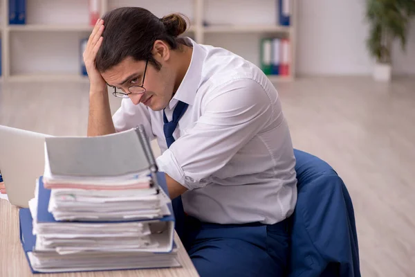 Joven empleado masculino y mucho trabajo en la oficina — Foto de Stock