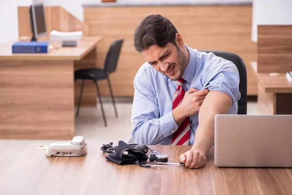 Jovem trabalhador masculino que sofre de hipertensão no local de trabalho — Fotografia de Stock