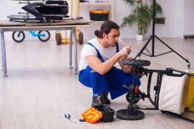 Genç erkek tamirci perambulator tamir ediyor.