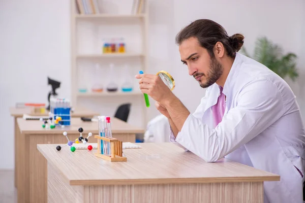 Młody chemik siedzi przy biurku w klasie. — Zdjęcie stockowe